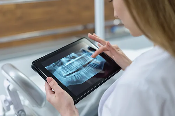 A dentist reviews a patient's digital xrays on her tablet device A dentist reviews a patient's digital xrays on her tablet device